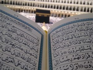 Coran ouvert avec vu sur la Kaaba en fond.