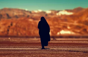 Femme couverte d'un long vêtement noir en plein desert.